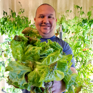 Man holding bunch of lettuce in front of two Gardyns