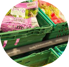 Photo of green grocery store bins on a shelf with bagged lettuce